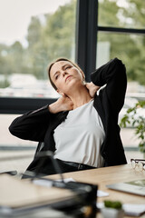 Middle-aged woman in distress sits on office chair.