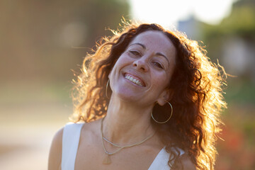 Beautiful middle age woman smiling. Back light at sunset.
