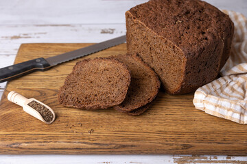 Rye Borodino (Borodinskiy) bread with a crispy crust on a wooden board, cut into slices. Homemade baking in rustic style. Selective focus, close-up.
