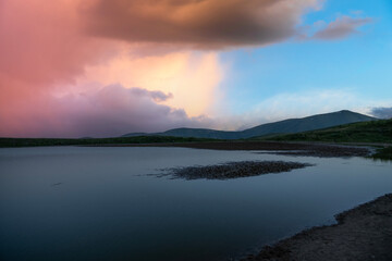 Beautiful  mountains landscape. Small lake in the mountains at the sunset. 