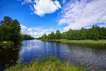 Beautiful summer river at sunny day with clouds reflection in the water