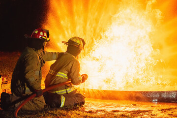 Two firefighters are sitting on the ground next to a fire hydrant