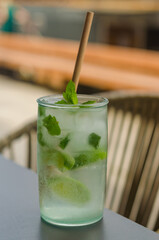 cold Mojito cocktail with rum, lime, ice cubes and mint with organic paper straw. High quality photo
