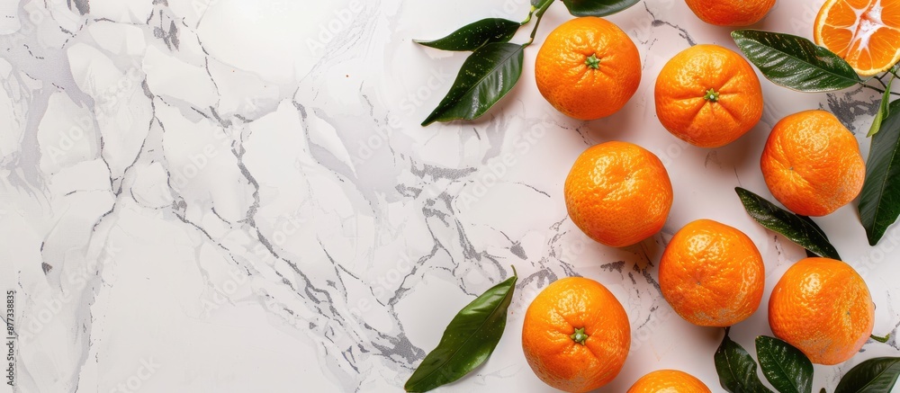 Poster top view of clementines with leaves on a white marble surface offering ample copy space in the image