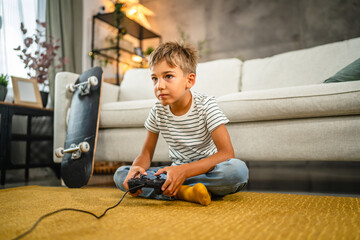 young boy sit on the floor and play video games on joystick at home