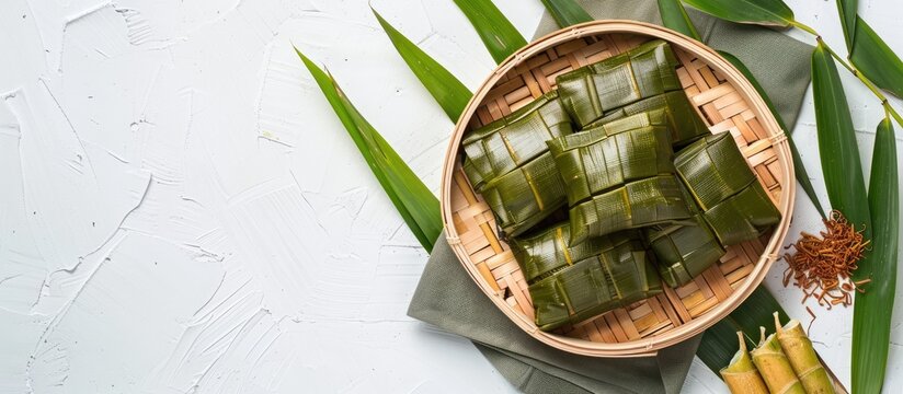 Traditional Chinese zongzies set on a plate with bamboo leaves for Dragon Boat Festival on a white background with a copy space image