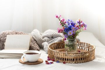 Cup of tea, a bouquet of wildflowers, book and knitted element.