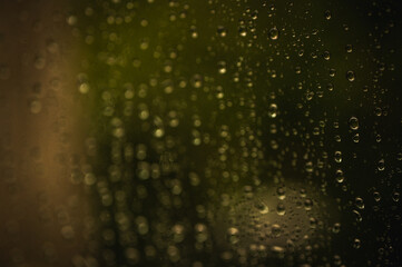 background of raindrops on glass, cloudy day with sunbeam, selective focus