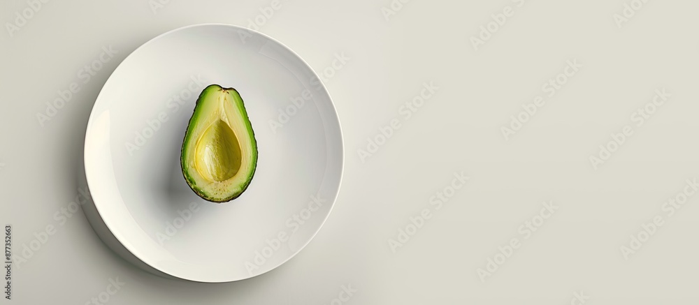 Poster top view of a ripe avocado on a white plate against a light background with copy space image embodyi