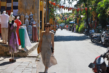Fototapeta premium tourist wear sun glasses and walk alone in the alley of Hoi An old town, Vietnam
