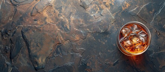 Top down shot of a whisky glass with ice on a dark stone surface featuring a blank space for text or graphics and color adjusted for a specific mood. Copy space image