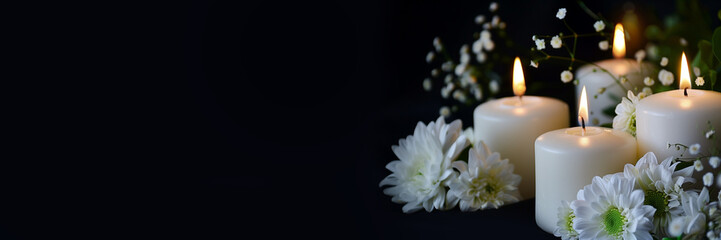 White candles and flowers on black panoramic background with copy space, funeral service, memorial and obituary header