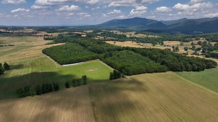 Beautiful peaceful landscape with Blue Ridge Mountains in Virginia and farmland with green fields and pastures under blue sky and clouds on summer day in American Southland