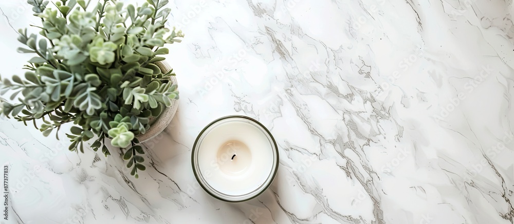 Poster modern work desk with a plant candle on a white marble background seen from above providing space fo