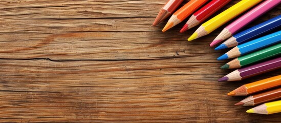Top view of colored pencils on a wooden surface displaying a stationery concept with room for a copy space image