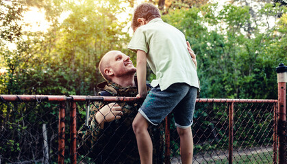 Shot of a father returning from the army hugging his son outside.