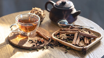 Tea ceremony, glass cup of black tea and teapot, different types of spices.