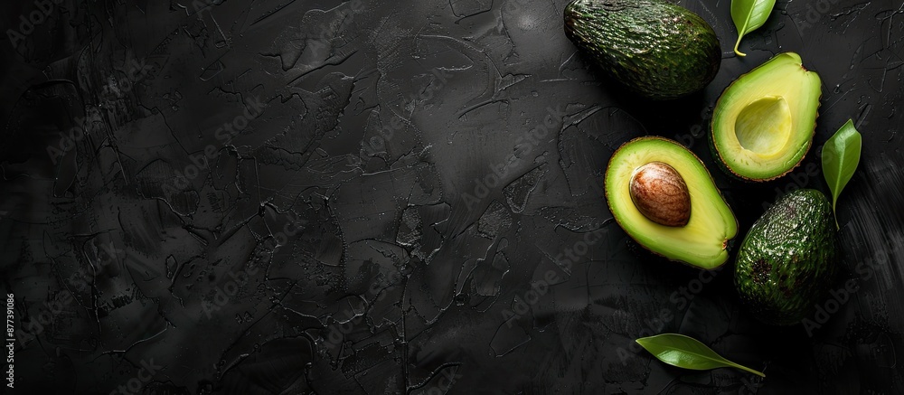 Aufkleber top down view of ripe avocado on black textured backdrop with ample copy space image