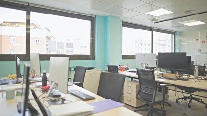 Bright and modern open office space with multiple desks and computers.