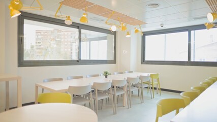 Bright and modern office cafeteria with tables and chairs.