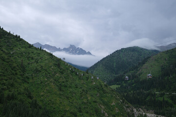 landscape with mountains, rain clouds and moving cable car cabins