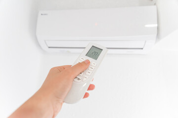 Hand Holding Remote Control Adjusting Air Conditioner