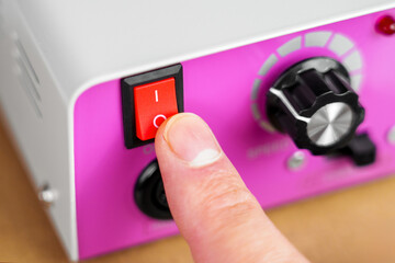 Pressing the red start switch of an electrical device with pink control panel