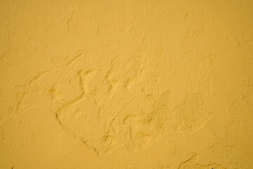 Yellow paint on the old rough concrete wall, weathered rough painted wall with patterns of cracks and peeling