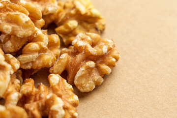 Walnut halves scattered on a brown paper surface close up. Raw ingredient