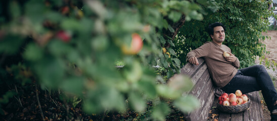 Fototapeta premium A male farmer is sitting on a bench in the garden