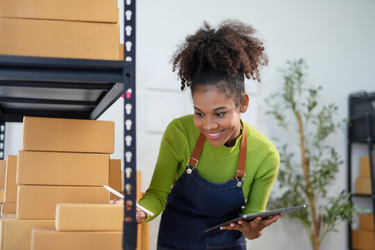 Smiling young manager uses digital tablet to check inventory levels in warehouse, seems to be enjoying her job
