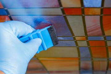Person applying sticky back plastic stained glass film to a glass shower screen. Smoothing out air...