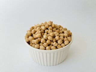 Raw dry chickpea in small ceramic bowl on white background. Traditional ingredient for cooking hummus. Middle Eastern and Mediterranean cuisine. Selected focused
