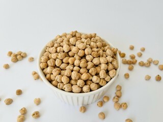 Raw dry chickpea in small ceramic bowl on white background. Traditional ingredient for cooking hummus. Middle Eastern and Mediterranean cuisine. Selected focused