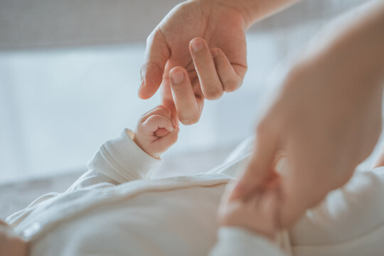 Close-up little hand of child baby holding hand of mother, A newborn holds on to mom's, dad's finger, Love and relationship with infant, Care and support, Dreaming and protection