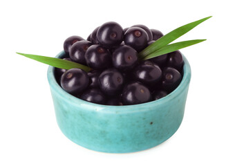 Fresh ripe acai berries in bowl and green leaves isolated on white