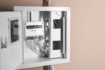 Electric meter in fuse box on beige wall. Energy measuring device
