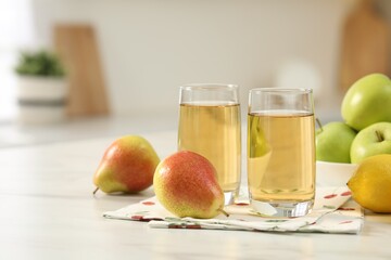 Glasses of fresh juice and fruits on white marble table in kitchen