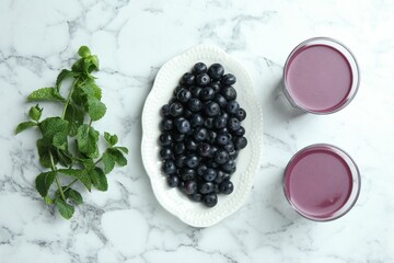 Tasty fresh acai juice in glasses, mint and berries on white marble table, flat lay