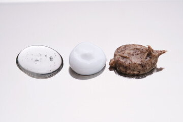 Facial serum, scrub and cream on a stainless steel surface. Texture.