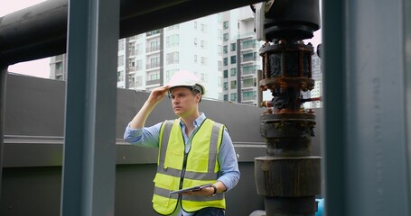 A Engineer man looking inspecting maintenance insulated pipelines valve pump control on the roof at...