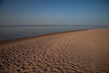 Sandy beach on the seashore. Desert at sunset. Yellow sand. Beautiful sky.