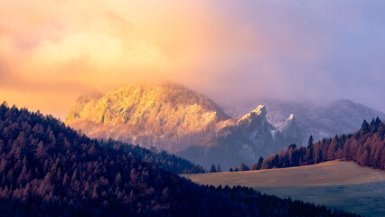 The first snow falling on the hills of the Biele Karpaty mountain range. In the foreground is a coniferous forest and a meadow. © Jan Haz