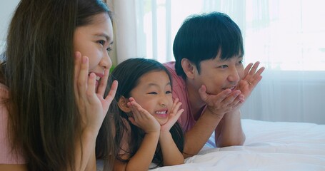 Obraz premium A joyful moment Asian family parents and child spending quality time together on a bed with a smiling in cozy bedroom, showcasing love and togetherness capturing the essence of family bonding.