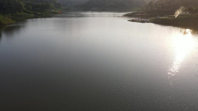 Aerial view of sunset on Sermo lake, Yogyakarta, Indonesia, with sun reflections over the clear water.