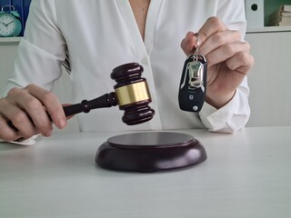 Person Holding Car Keys and Gavel in Courtroom