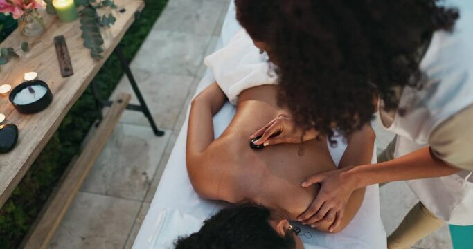 Aromatherapy, hotel and women with hot stone massage for holistic healing, spa or self care. Top view, zen and female client with hospitality service by pool for candle, scent or muscle treatment