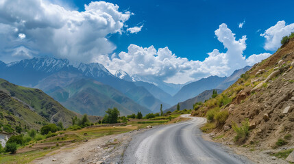 Fototapeta premium A picturesque road winding through the mountains under a clear sky with fluffy clouds in the background. This view exudes peace and beauty of nature, inviting you to travel through the landscape.
