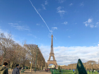The Eiffel Tower viewed from Champ de Mars against a clear blue sky. The iconic iron structure...