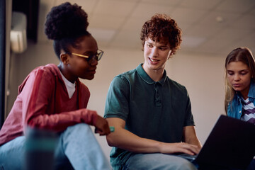 Obraz premium Young students cooperating while using laptop and learning in classroom.